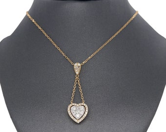 Puede incluir: Un collar de oro con un colgante en forma de corazón adornado con diamantes brillantes. El colgante cuelga de una cadena delicada y presenta un diseño de doble cadena.