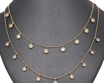 May include: A gold necklace with two layers of delicate chains and small round diamond accents hanging from each chain.