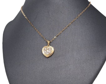Puede incluir: Un collar de cadena de oro con un colgante en forma de corazón engastado con pequeños diamantes.