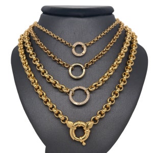 May include: Four gold chains with different link styles and diamond-encrusted circle pendants. The bottom chain has a large, round, gold clasp.