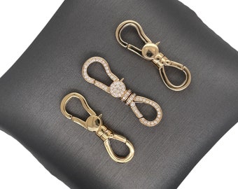 May include: Three gold-toned keychains with a decorative design. Two of the keychains have a circle of clear stones around the metal loop. The third keychain has a plain metal loop.