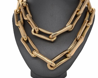 May include: A thick gold chain necklace with large, rectangular links. The necklace is displayed on a gray mannequin bust.