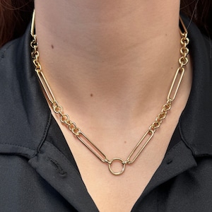 May include: A gold chain necklace with a large, round, open circle pendant.