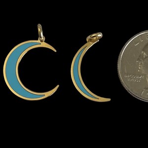K&ouml;nnte beinhalten: Drei goldene Halbmond-Anh&auml;nger mit blauem Emaille. Die Anh&auml;nger sind in verschiedenen Gr&ouml;&szlig;en und werden neben einem US-amerikanischen Viertel f&uuml;r die Skalierung gezeigt.