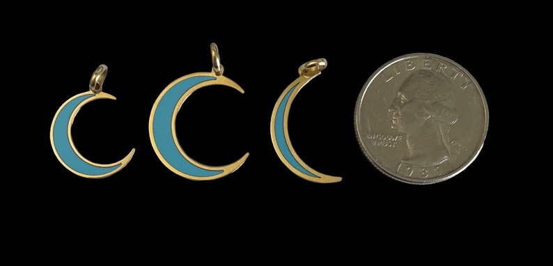 K&ouml;nnte beinhalten: Drei goldene Halbmond-Anh&auml;nger mit blauem Emaille. Die Anh&auml;nger sind in verschiedenen Gr&ouml;&szlig;en und werden neben einem US-amerikanischen Viertel f&uuml;r die Skalierung gezeigt.