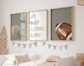 May include: Three framed wall art prints with a football theme. One print features a football helmet, another reads "EAT SLEEP FOOTBALL REPEAT", and the third shows a football. The prints are above a white bed with a beige quilt.