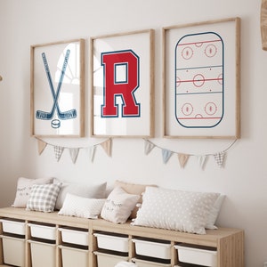 Puede incluir: Una pared blanca con tres impresiones enmarcadas. Las impresiones muestran un palo de hockey y un disco, una letra R roja y una pista de hockey. Un banco de madera con contenedores de almacenamiento blancos se encuentra frente a las impresiones.