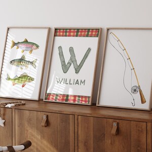 May include: Three framed prints with a fishing theme. The first print features three watercolor fish, the second print has a large letter W with the name William below it, and the third print shows a fishing rod and reel.