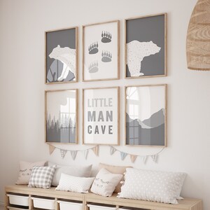 May include: A nursery room with a wooden bench with storage bins, a giraffe stuffed animal, and six framed prints on the wall. The prints feature a bear, paw prints, mountains, and the text "Little Man Cave".