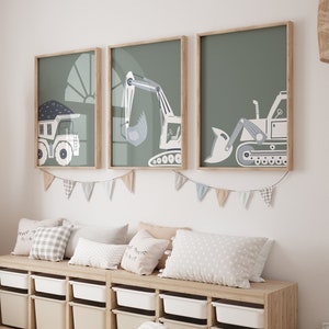 Peut inclure: Trois impressions encadrées de véhicules de chantier sur fond vert sauge. Les impressions sont accrochées à un mur blanc au-dessus d'un banc de rangement en bois avec des bacs de rangement blancs. Le banc est doté de plusieurs coussins aux motifs variés.