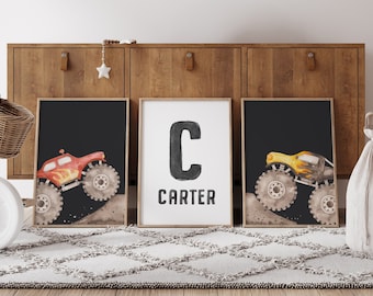 May include: Three framed prints with a monster truck theme. The left and right prints feature a black background with a red and yellow monster truck, respectively. The center print has a white background with a black letter C and the name Carter.
