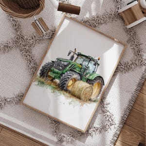 Może przedstawiać: Akwarela przedstawiająca zielony traktor z ż&oacute;łtymi kołami i belą siana. Grafika jest oprawiona w jasną drewnianą ramę. Obraz znajduje się na białej powierzchni z szaro-białym wzorzystym dywanem.