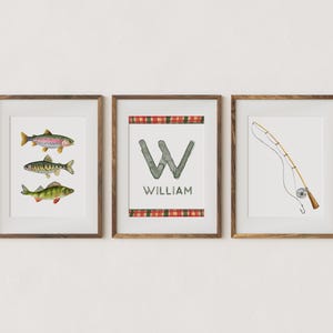 May include: Three framed prints with a fishing theme. The first print features three watercolor fish, a rainbow trout, a perch, and a bass. The second print features a watercolor letter W with the name William below. The third print features a watercolor fishing rod and reel.