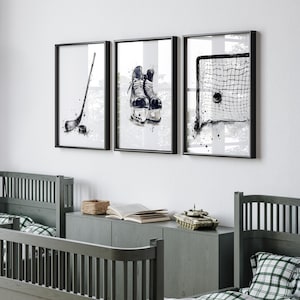 Pode incluir: Um conjunto de tr&ecirc;s quadros decorativos com ilustra&ccedil;&otilde;es a preto e branco em estilo aguarela de equipamento de h&oacute;quei no gelo, incluindo um stick de h&oacute;quei com um disco, um par de patins e uma baliza com um disco dentro da rede.