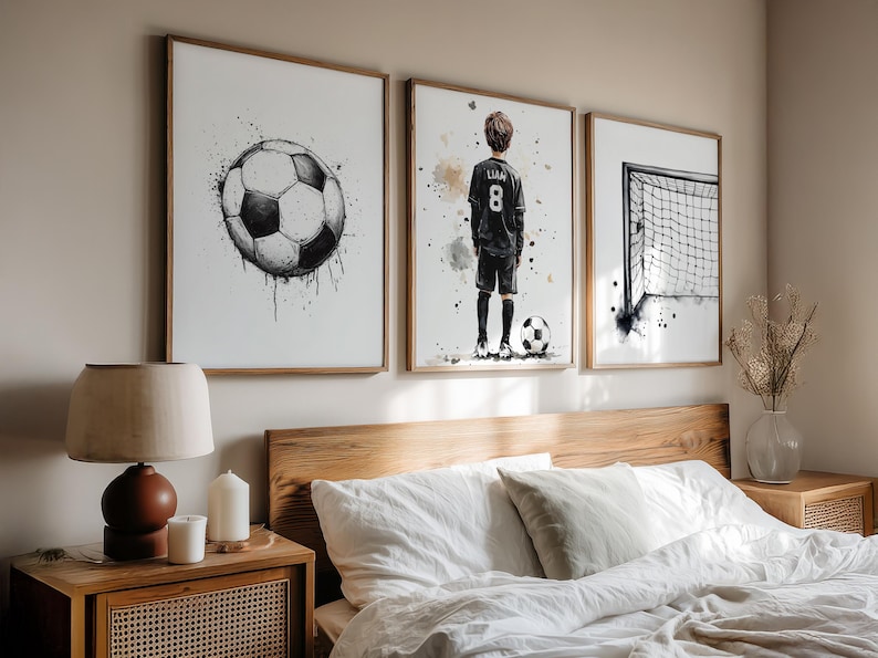 May include: Set of three framed art prints featuring watercolor-style soccer-themed illustrations. Includes a soccer ball, a soccer player with the name "Liam" and the number 8 on the jersey, and a soccer goal. The artwork is in black and white with brown wooden frames.
