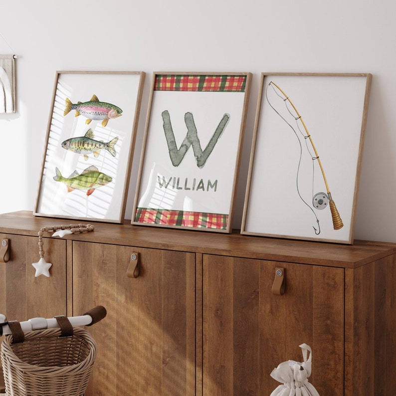 May include: Three framed prints with a fishing theme. The first print features three watercolor fish, the second print has a large letter W with the name William below it, and the third print shows a fishing rod and reel.