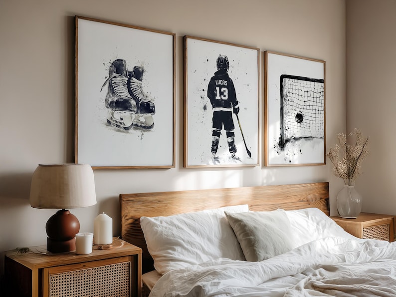 May include: Three framed watercolor prints depicting hockey themes. The prints feature a pair of skates, a hockey player with the number 13, and a hockey net with a puck. The artwork is in black and white with a watercolor effect, set in wooden frames.