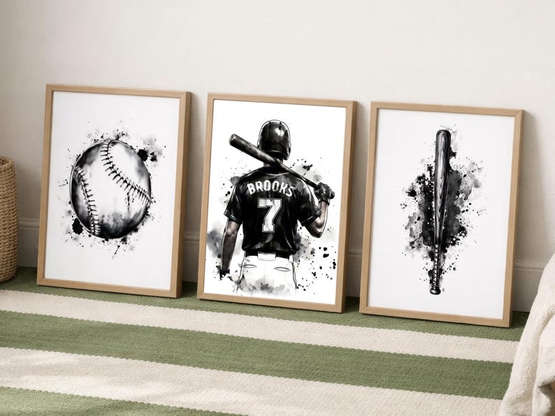 May include: Three framed wall art prints featuring black and white watercolor-style illustrations of baseball equipment. The left print shows a baseball, the center print depicts a player with the name BROOKS and number 7, and the right print shows a bat.
