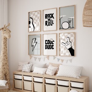 May include: Six framed prints with black and white illustrations of musical instruments, a lightning bolt, a hand making the rock and roll sign, and the words "Rock 'n' Roll" and "Cool Dude". The prints are arranged in a grid on a white wall above a wooden bench with pillows.