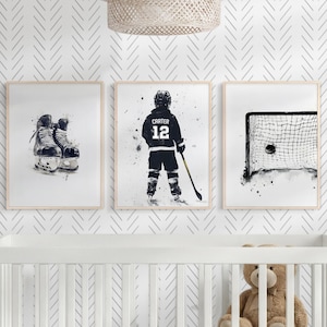 Pode incluir: Tr&ecirc;s quadros de parede com ilustra&ccedil;&otilde;es em aguarela a preto e branco de equipamento de h&oacute;quei no gelo. O quadro da esquerda mostra patins, o central um jogador com o texto CARTER 12 e o da direita mostra uma baliza de h&oacute;quei.