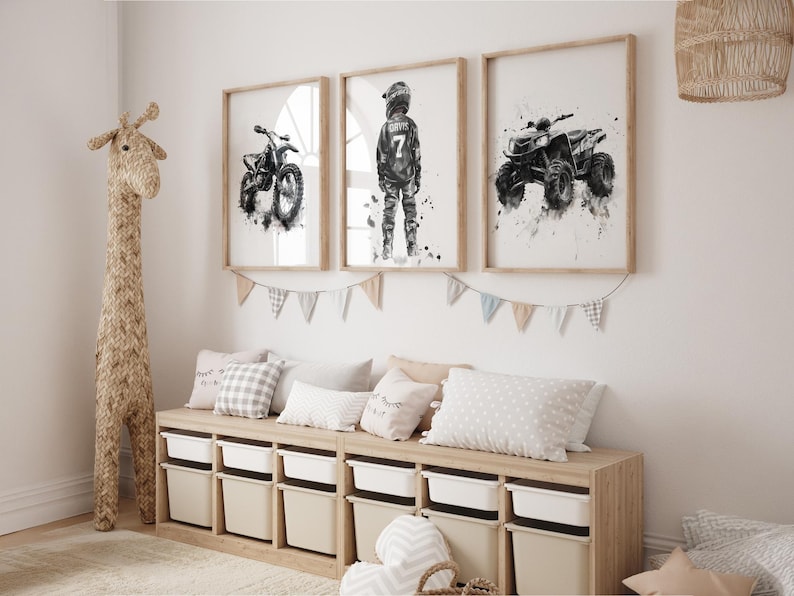 May include: Three framed watercolor prints of a motorcycle, a motocross rider, and an ATV. The prints are in neutral tones and are displayed above a storage bench with white bins. A woven giraffe and decorative pillows complete the room.