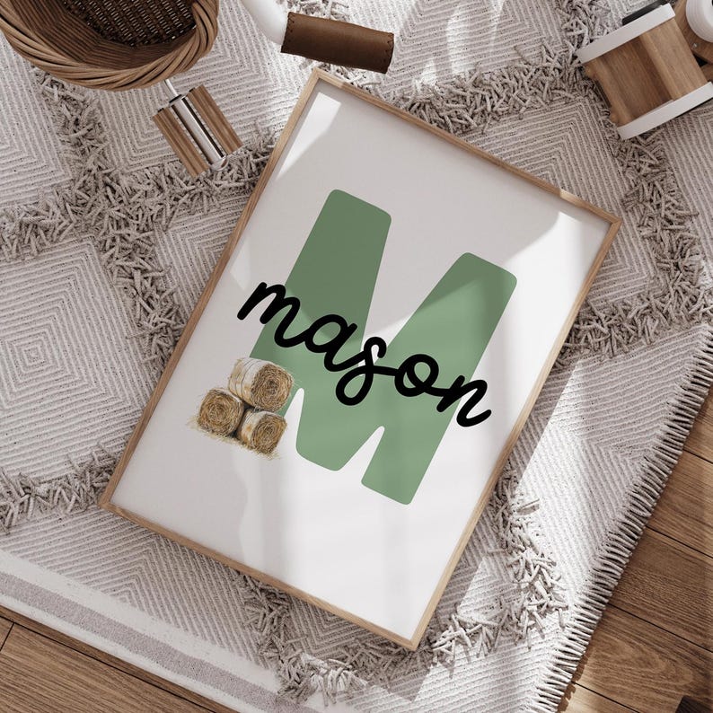 Może przedstawiać: Oprawiony wydruk z imieniem "mason" czcionką skryptową na dużym zielonym "M". Wydruk zawiera małą ilustrację bel siana. Rama jest w jasnym kolorze drewna.