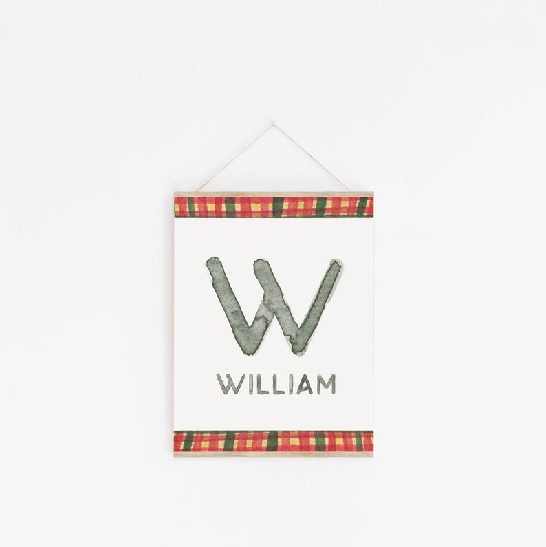 May include: A white sign with a gray watercolor letter W and the name William printed below. The sign is framed with a red and green plaid border.