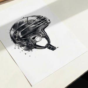 Pode incluir: Uma ilustra&ccedil;&atilde;o em aguarela a preto e branco de um capacete de h&oacute;quei. A obra apresenta um perfil detalhado do equipamento de prote&ccedil;&atilde;o com ranhuras de ventila&ccedil;&atilde;o vis&iacute;veis, uma tira de queixo e salpicos de tinta art&iacute;sticos ao redor.