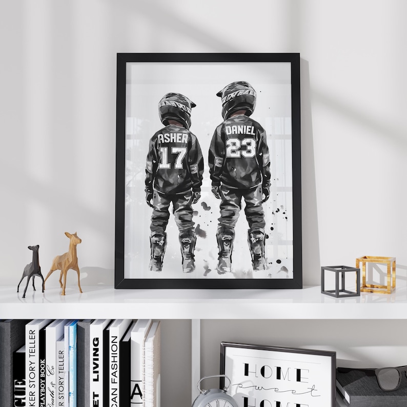 May include: A framed black and white art print featuring two motocross riders standing side by side. The left rider wears a jersey with the name ASHER and number 17, while the right rider wears a jersey with the name DANIEL and number 23.