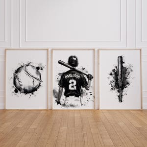 May include: A set of three black and white watercolor-style art prints. The left print shows a baseball, the center print depicts a baseball player wearing a jersey with the name HASLEDON and number 2, and the right print features a baseball bat.