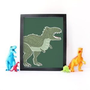 Op de afbeelding: Een ingelijst afdruk van een groene dinosaurus met een donkergroene achtergrond. De dinosaurus kijkt naar rechts en heeft zijn mond open. De afdruk is in een zwart frame.