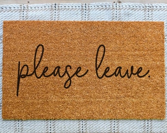 May include: A brown coir doormat with the text "Please leave." in black cursive lettering.