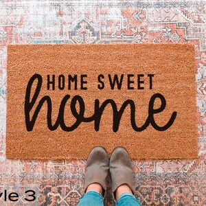 May include: A brown coir doormat with the text "Home Sweet Home" in black cursive lettering.