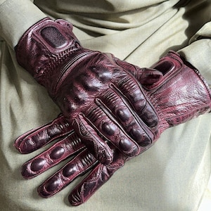 May include: A pair of burgundy leather motorcycle gloves with reinforced knuckles and fingertip protection.