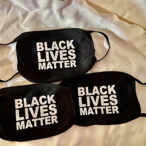 May include: Three black face masks with the words "Black Lives Matter" printed in white glitter on each mask.