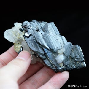 May include: A cluster of black and silver crystals with a metallic sheen. The crystals are arranged in a jagged, irregular shape. Some of the crystals are translucent and have a glassy appearance.