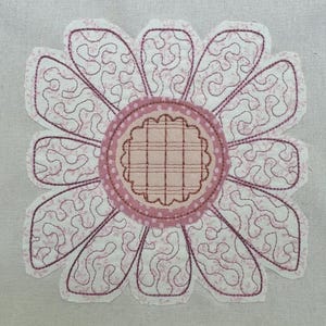 Puede incluir: Aplicación de tela de una flor de margarita con pétalos rosas y blancos. Los pétalos tienen un patrón detallado y arremolinado. El centro de la flor es un diseño de cuadros rosa claro, rodeado por un círculo rosa punteado.