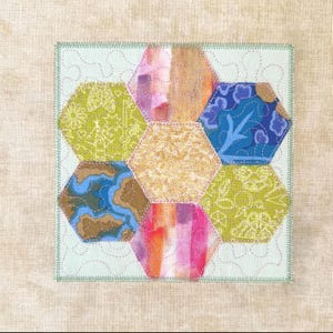 May include: A square fabric quilt block featuring seven hexagonal patches in various colours and patterns, including lime green, blue, orange, and gold. The hexagons are arranged in a flower shape on a light mint background with visible stitching.