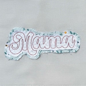 May include: A white fabric patch with the word "Mama" embroidered in red thread. The fabric has a distressed, frayed edge.