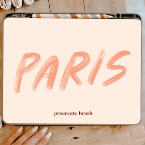 May include: A digital tablet displaying the word "PARIS" in a pink brush font. The text "procreate brush" is displayed below the word "PARIS".