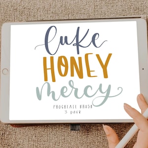 Può includere: Uno schermo di tablet digitale che mostra un design scritto a mano con il testo "Like Honey Mercy" in blu, arancione e grigio. Il testo "Procreate Brush 3 Pack" è anche visibile sullo schermo.