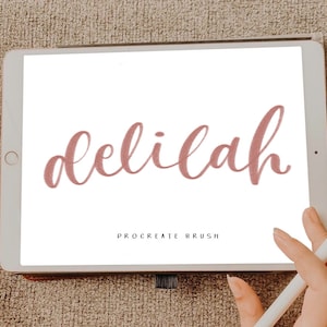 May include: A digital illustration of the word "delilah" written in a pink cursive font on a white background. The text is displayed on a tablet screen with a white stylus resting on the screen.