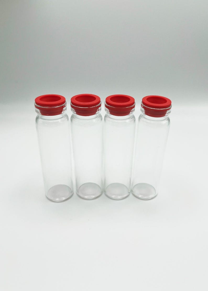 May include: Four clear glass vials arranged in a row, each featuring a cylindrical body with a flat base and a narrow neck. Every vial is topped with a bright red silicone stopper that fits securely into the opening at the top of the glass container.