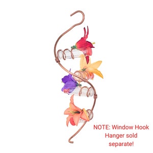 May include: A copper-colored, spiral-shaped hummingbird feeder with clear glass tubes and colorful artificial flowers. The feeder has a hook for hanging and is designed to attract hummingbirds. The flowers are red, orange, yellow, and purple.