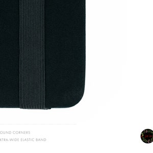 May include: Close-up of a black notebook with rounded corners and an extra-wide elastic band.
