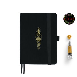 Peut inclure: Un carnet noir avec un motif de système solaire doré et une fermeture élastique noire. Le carnet a un élastique noir et un motif en feuille d'or.
