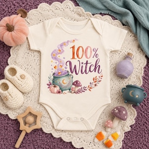 May include: A cream-colored baby bodysuit featuring a graphic print of a cauldron with purple smoke, candy corn, mushrooms, and the text 100% Witch. The design includes autumn-themed floral accents in shades of orange, purple, and green.