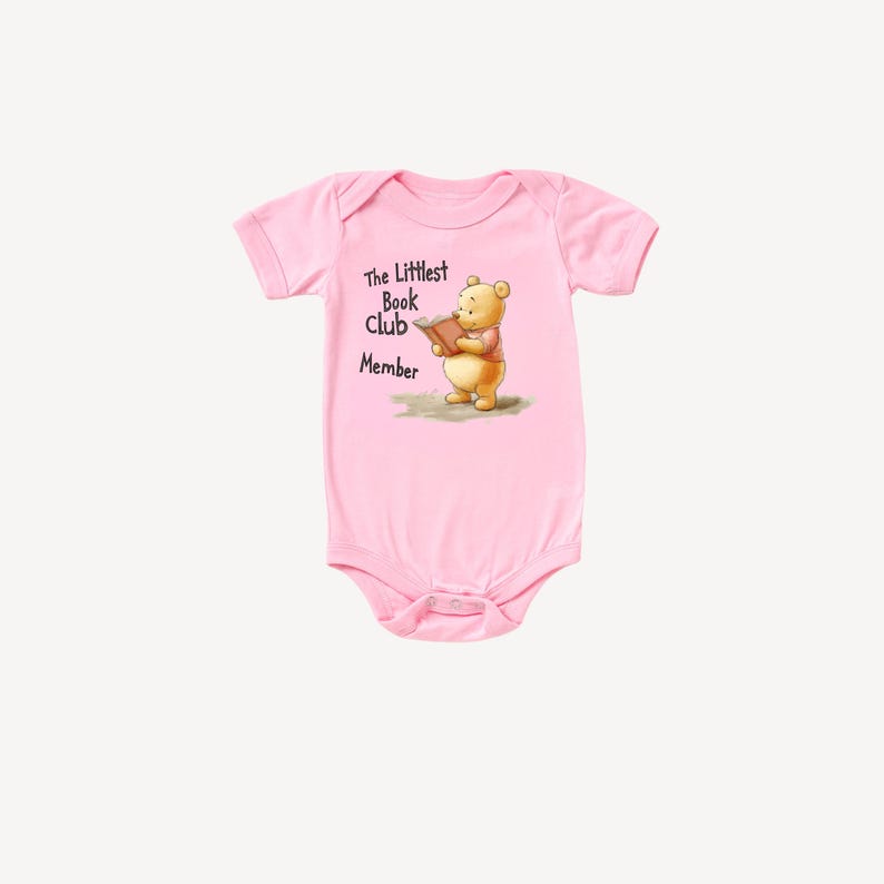 May include: Pink baby bodysuit with short sleeves. The bodysuit features an illustration of a bear reading a book, with the text "The Littlest Book Club Member". The bodysuit is made of soft material.