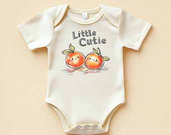May include: Cream baby bodysuit with short sleeves. The front displays a watercolour illustration of two smiling oranges with green leaves and the text "Little Cutie". The bodysuit has snap closures.