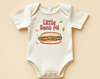 May include: Cream-colored baby onesie with the text "Little Banh Mi" above a cartoon illustration of a Banh Mi sandwich. The sandwich has layers of bread, vegetables, and meat. The onesie has short sleeves and snap closures.